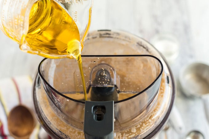 adding olive oil to food processor