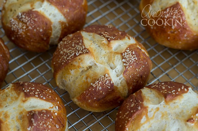 A close up of bretzel rolls resting on a wire cooling rack.