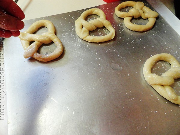 An overhead of homemade German pretzel dough in pretzel shape laying on a baking sheet.