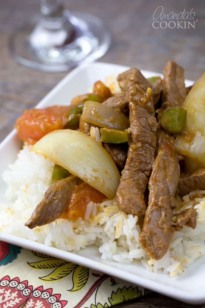 A close up of a white plate with white rice and Chinese pepper steak on top.
