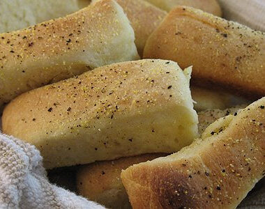 A close up photo of pull apart cornmeal dinner rolls in a basket.