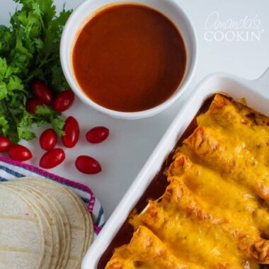 enchiladas in a pan and bowl of emchilada sauce