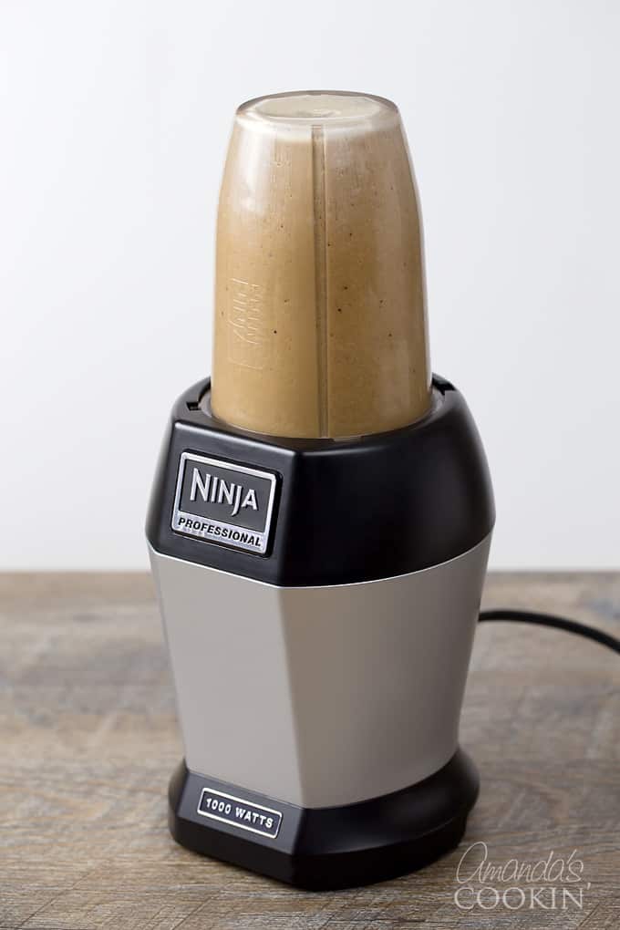 A ninja blender blending a mocha frappucino.