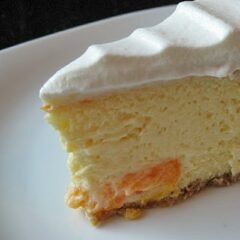 A close up photo of a slice of mandarin orange cheesecake on a plate.