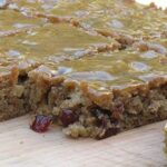 A close up photo of applesauce spice bars resting on a wooden cutting board.
