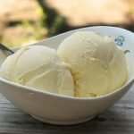 A close up of two scoops of white chocolate ice cream in a white bowl.