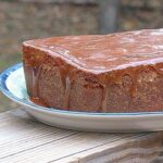 A close up photo of apple cider pound cake with caramel glaze resting on a plate.