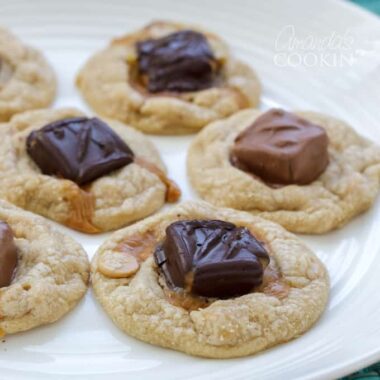 A close up photo of candy bar cookies resting on a white plate.