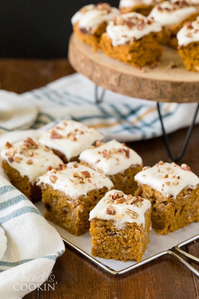 squares of pumpkin cake with a plate of cake in the background