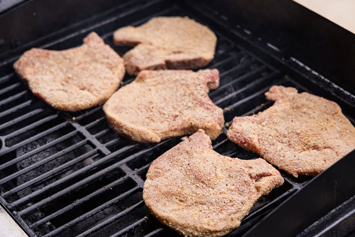 breaded raw pork chops on grill