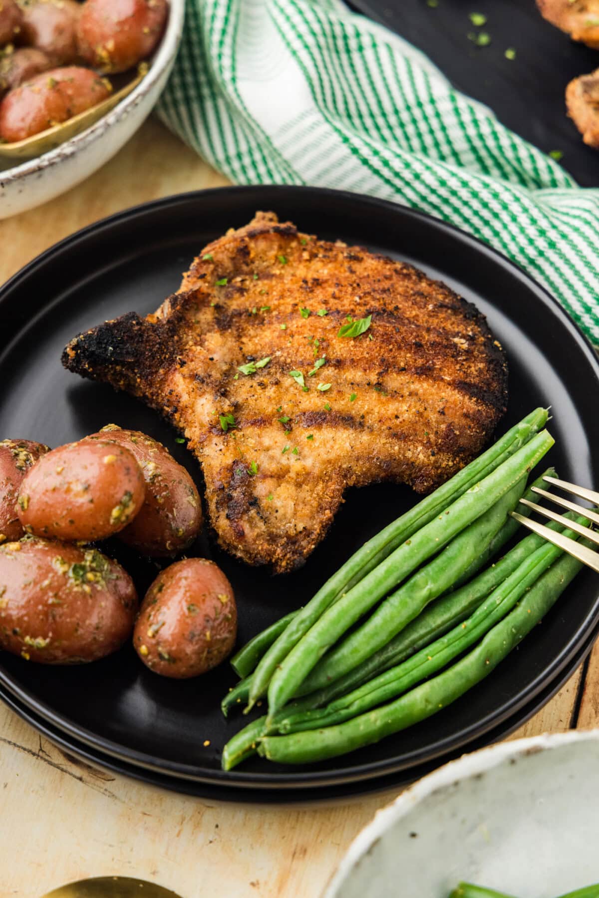 Grilled Breaded Pork Chop on plate with green beans and potatoes