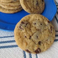 A close up photo of a buttermilk chocolate chip cookie with a plate of cookies in the background.