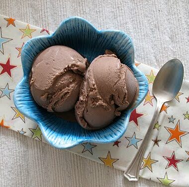 Mexican chocolate ice cream in a blue bowl with a spoon on the side.