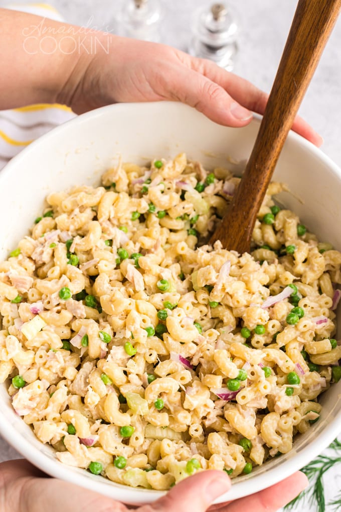 someone holding a big bowl of tuna pasta salad