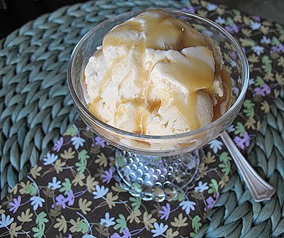 A close up picture of brown sugar vanilla bean ice cream in a clear bowl with caramel drizzle on top.