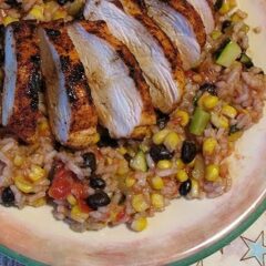 An overhead photo of a plate of spicy grilled chicken with baja black beans and rice.