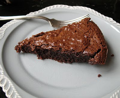 A close up photo of a slice of cast iron skillet brownie on a white plate served with a fork.