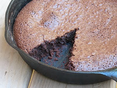 A close up photo of a cast iron skillet brownie with a slice missing.