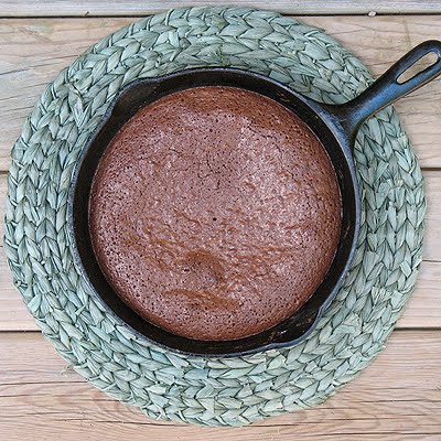 An overhead photo of a cast iron skillet brownie on a green placemat. 