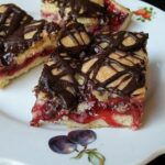 A close up photo of cherry pie squares on a white plate.