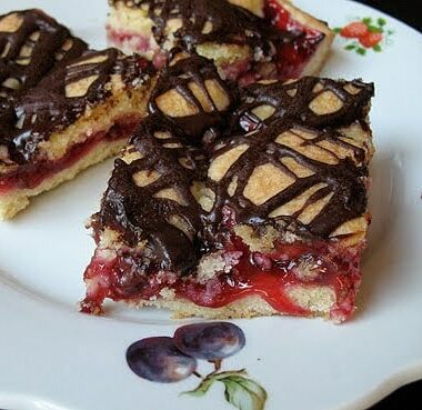 A close up photo of cherry pie squares on a white plate.