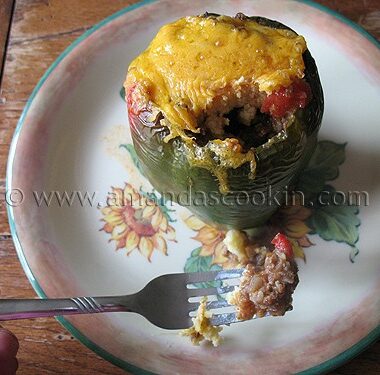 A close up photo of a forkful of chili and cornbread stuffed pepper with the whole stuffed pepper in the background.