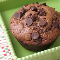 A close up photo of a chocolate chocolate chip muffin in a green dish.