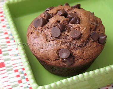 A close up photo of a chocolate chocolate chip muffin in a green dish.
