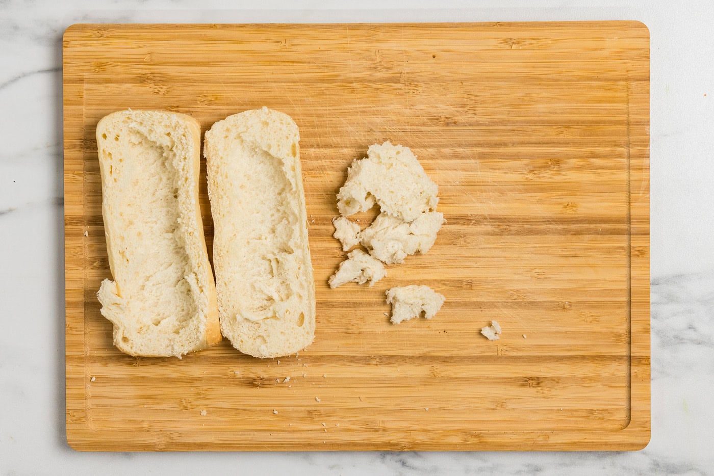 french rolls on cutting board with some of the bread removed