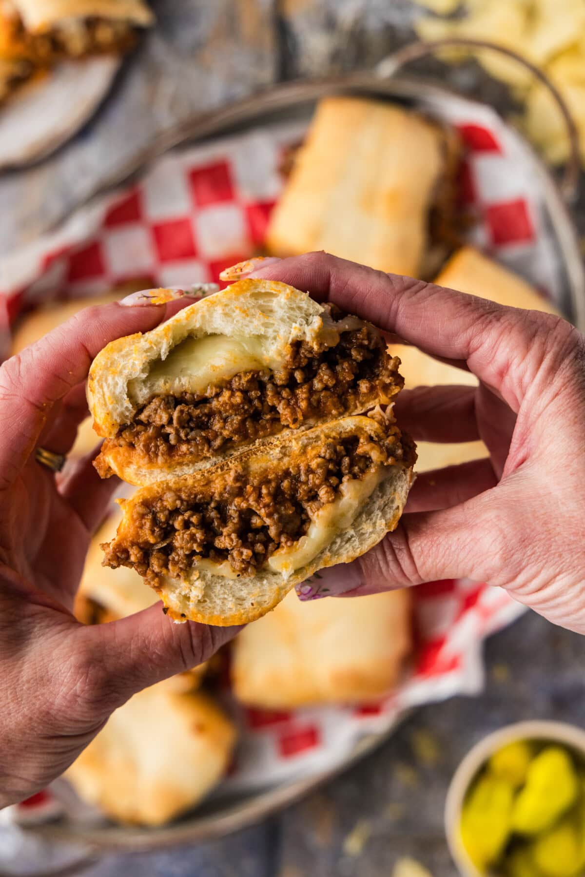 hands holding a guinea grinder sandwich that has been cut in half