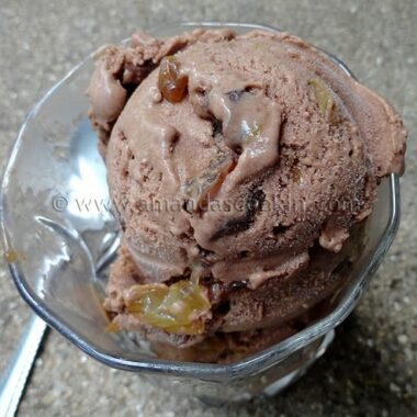 A close up photo of chocolate rum raisin ice cream in a clear dish.