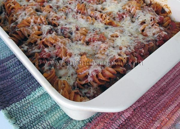 A close up photo of baked rotini with Italian sausage in a baking dish.
