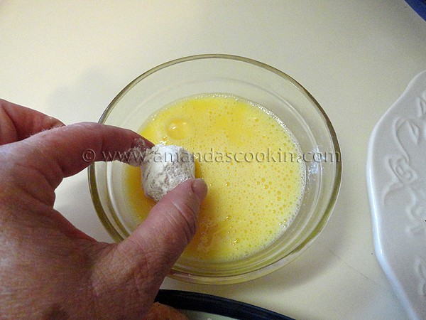 A photo of the floured ball being coated with egg.