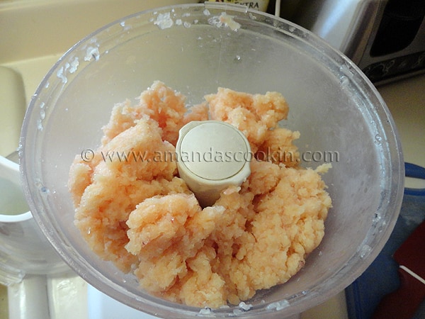 A photo of raw chicken in a food processor. 
