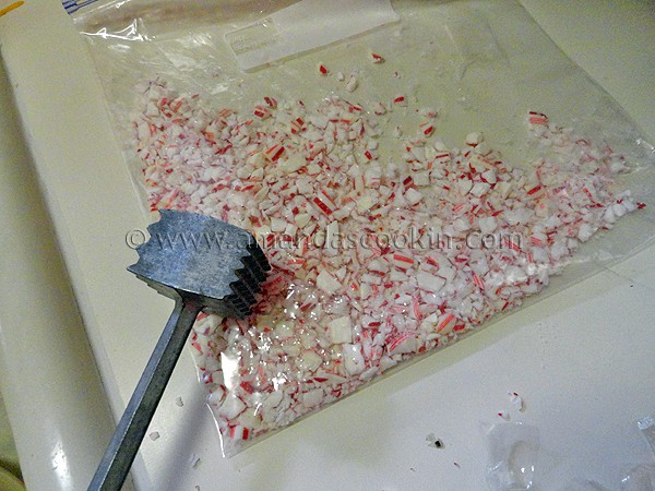 A bag of crushed peppermint candies with a meat mallet resting on top. 