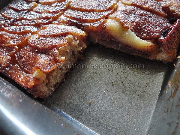 A close up photo of a Dutch apple snack cake with a piece missing.
