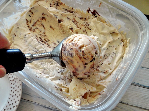 A close up photo of an ice cream scoop scooping out Nutella swirl cheesecake ice cream.