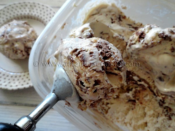 A close up photo of an ice cream scoop scooping Nutella swirl cheesecake ice cream.