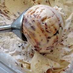 A close up photo of an ice cream scoop scooping Nutella swirl cheesecake ice cream.