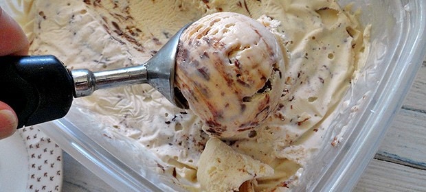 A close up photo of an ice cream scoop scooping Nutella swirl cheesecake ice cream.
