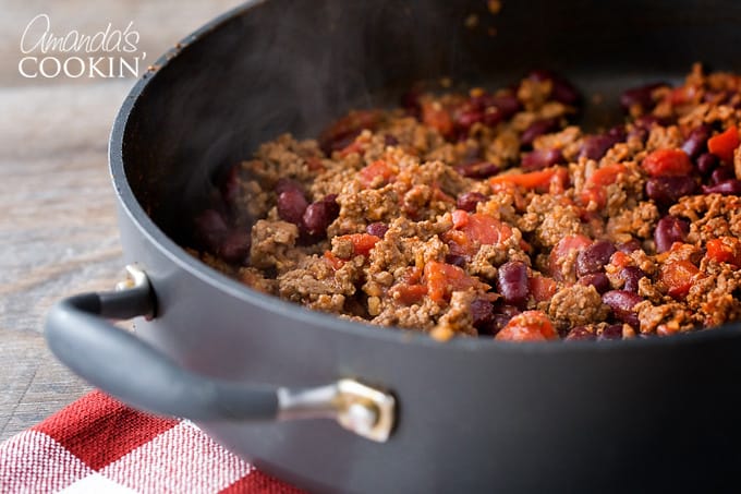 Brown ground beef in a skillet. Drain off fat from ground beef and return beef to pan. Add seasoning mixture, water, beans and tomatoes and stir to combine.