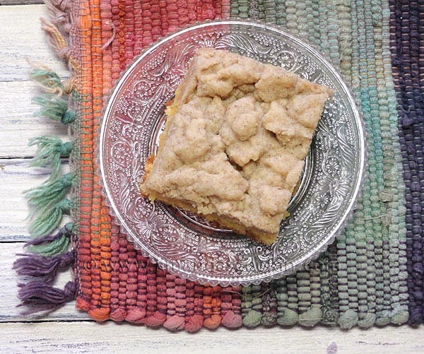 An overhead photo of a piece of crumb cake on a clear plate.