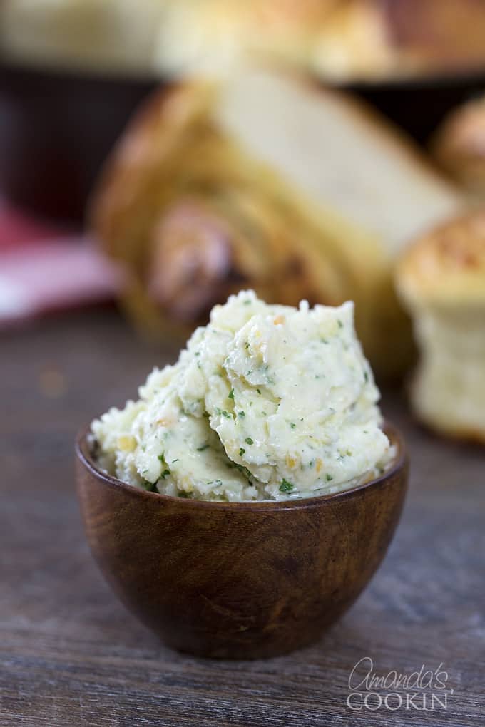 A close up of a wooden bowl filled with garlic butter.