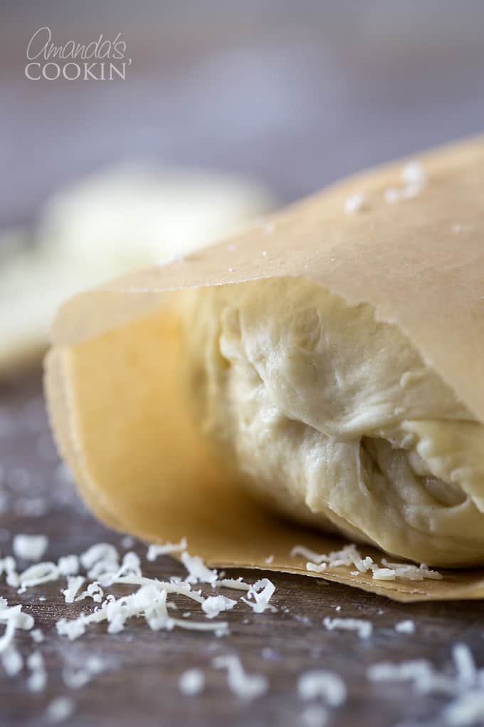 A close up photo of Parmesan garlic roll dough wrapped in parchment paper.