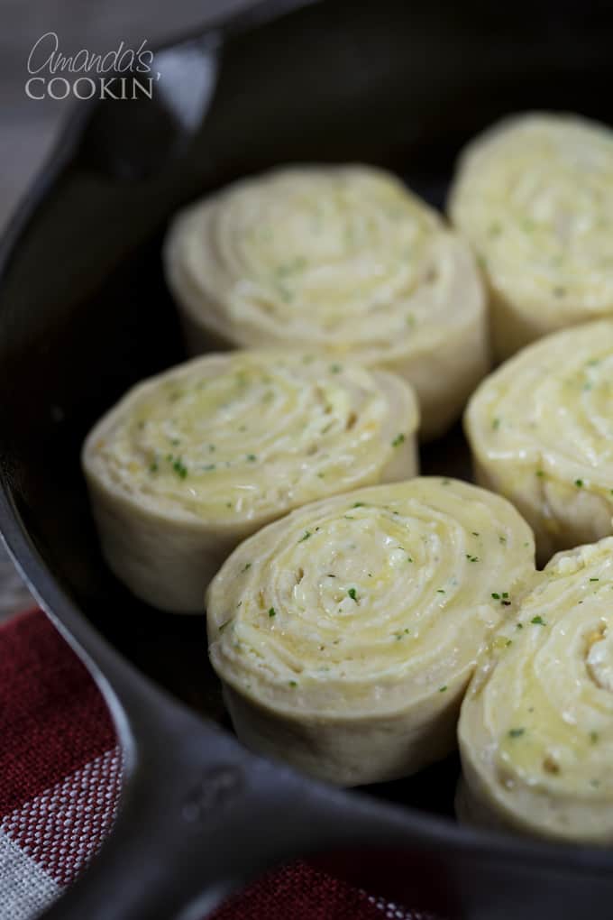 A close up of unbaked Parmesan garlic rolls in a cast iron skillet.