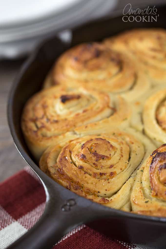 A close up of baked Parmesan garlic rolls in a cast iron skillet.