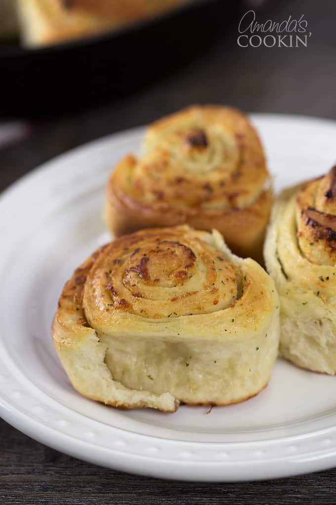 A white plate with three Parmesan garlic rolls.