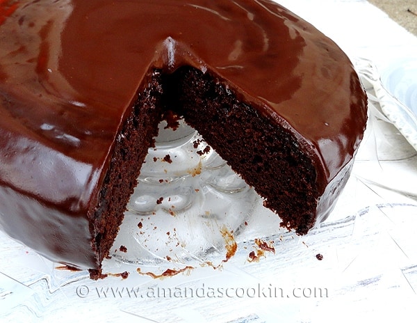 A close up photo of deep dark chocolate cake with a slice taken out.