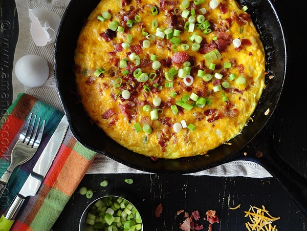 An overhead photo of a cheesy bacon potato frittata in a cast iron pan,