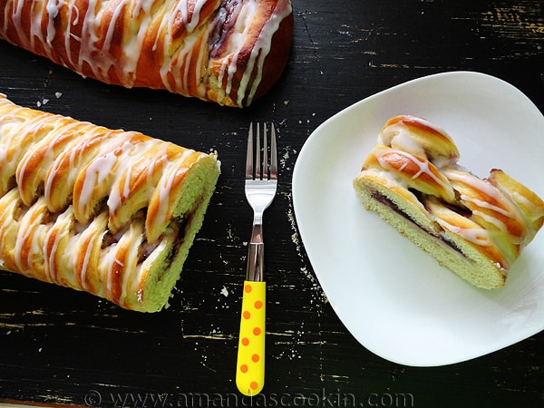 An overhead photo of braided blackberry breakfast Danishes with a slice served on a plate with a fork to the side.